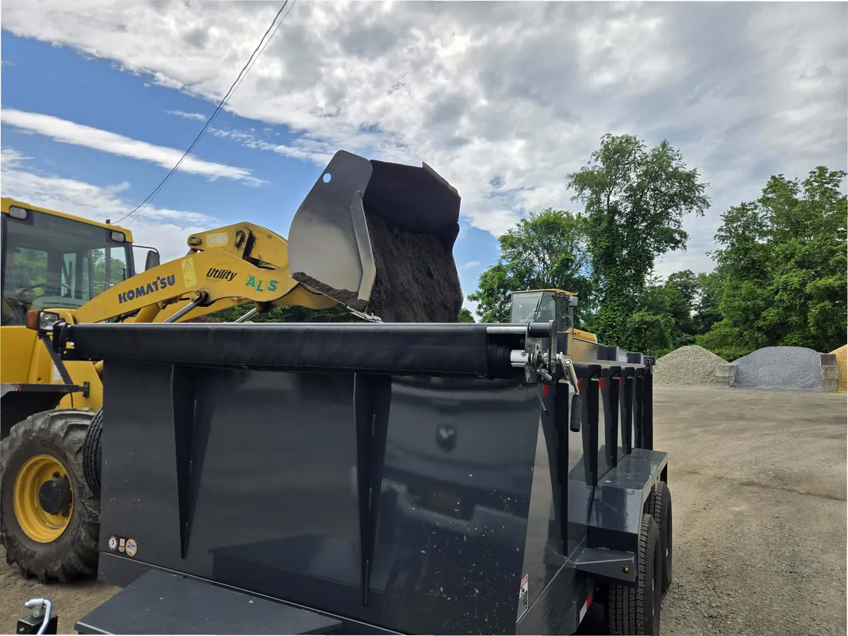 Wheel loader topping off the Mainline dump trailer with topsoil at a materials yard