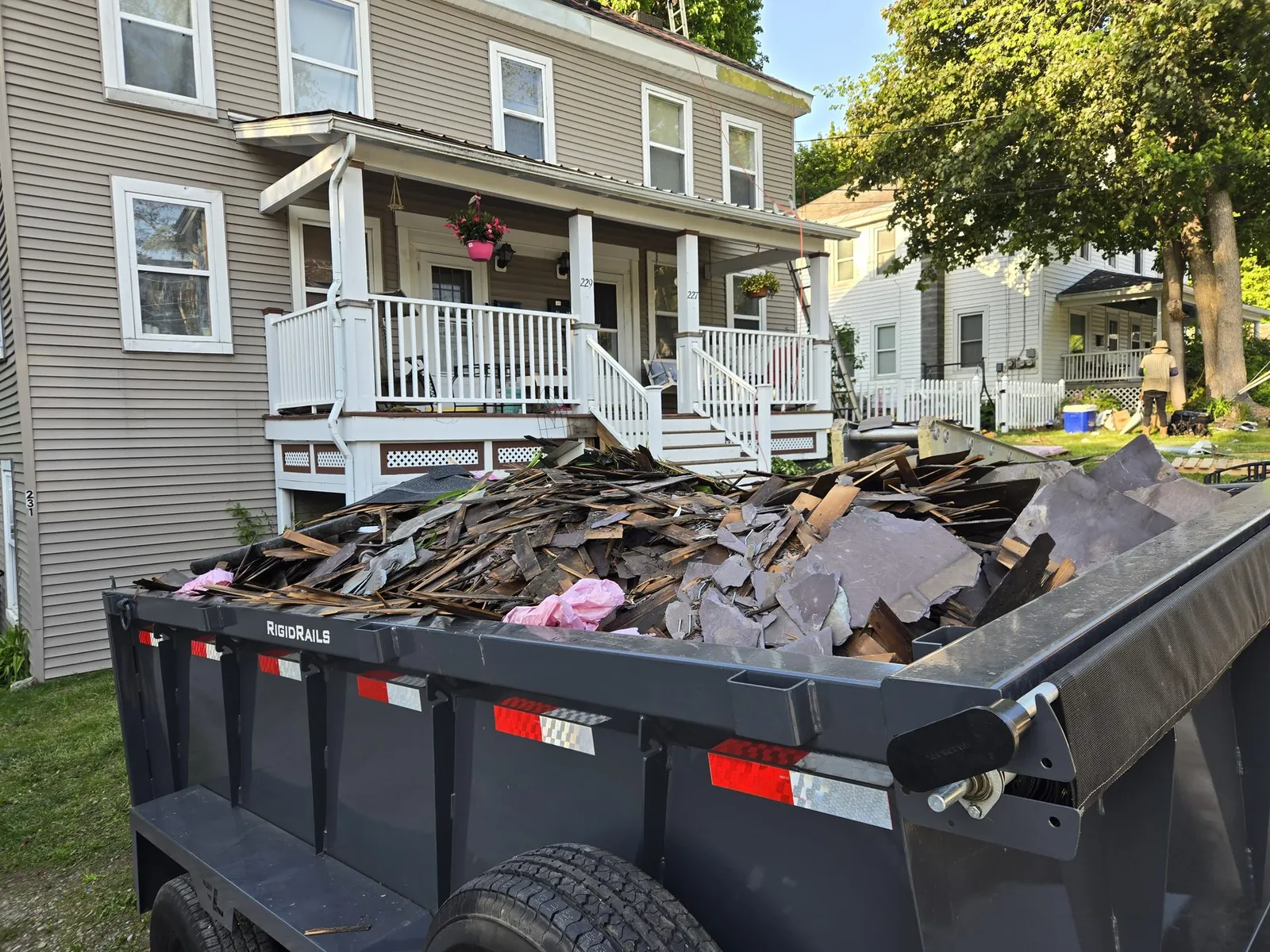 Dump trailer loaded with slate roofing tear-off debris at a residential job