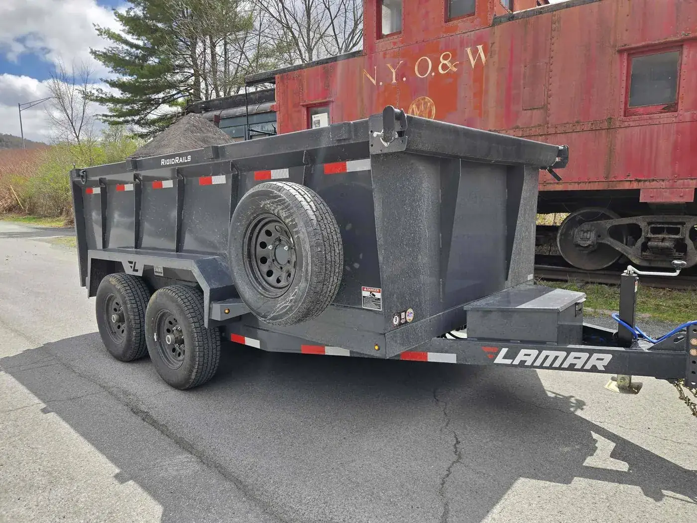 Mainline dump trailer parked beside a vintage New York, Ontario & Western railway caboose in the Hudson Valley
